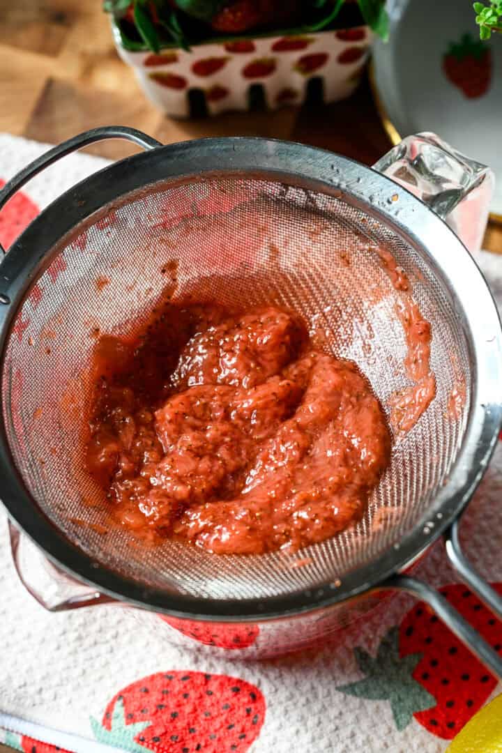 Overhead view of strawberry pulp in a strainer.