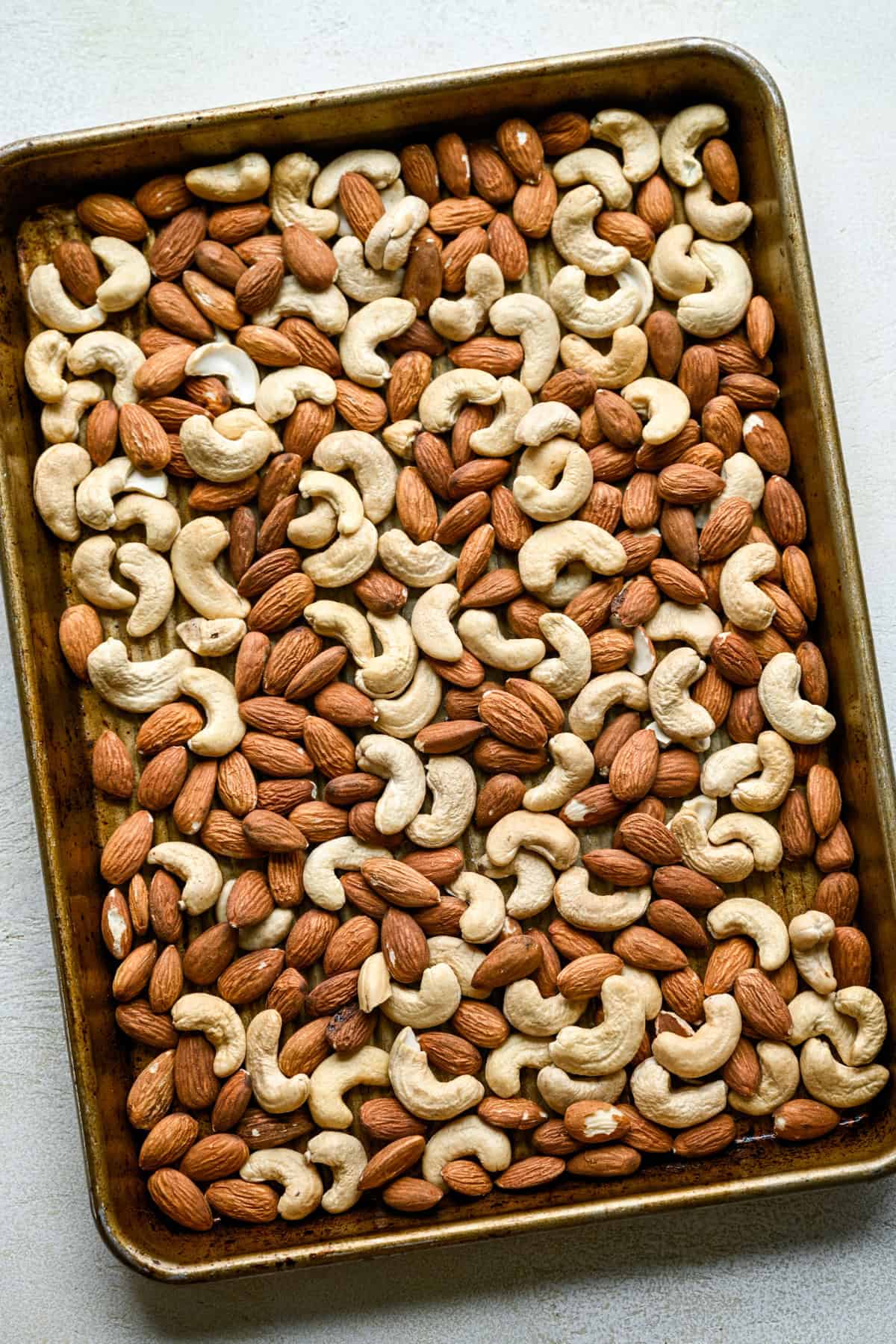 Roasted cashews and almonds on a sheet pan.