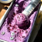 Blueberry lemon ice cream scooped out of a loaf pan with an ice cream scoop.