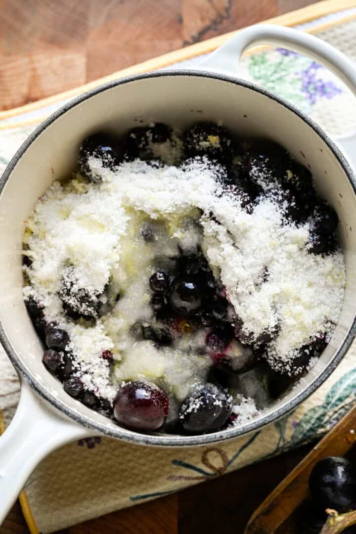 Overhead view of grapes sugar and lemon in a pot.