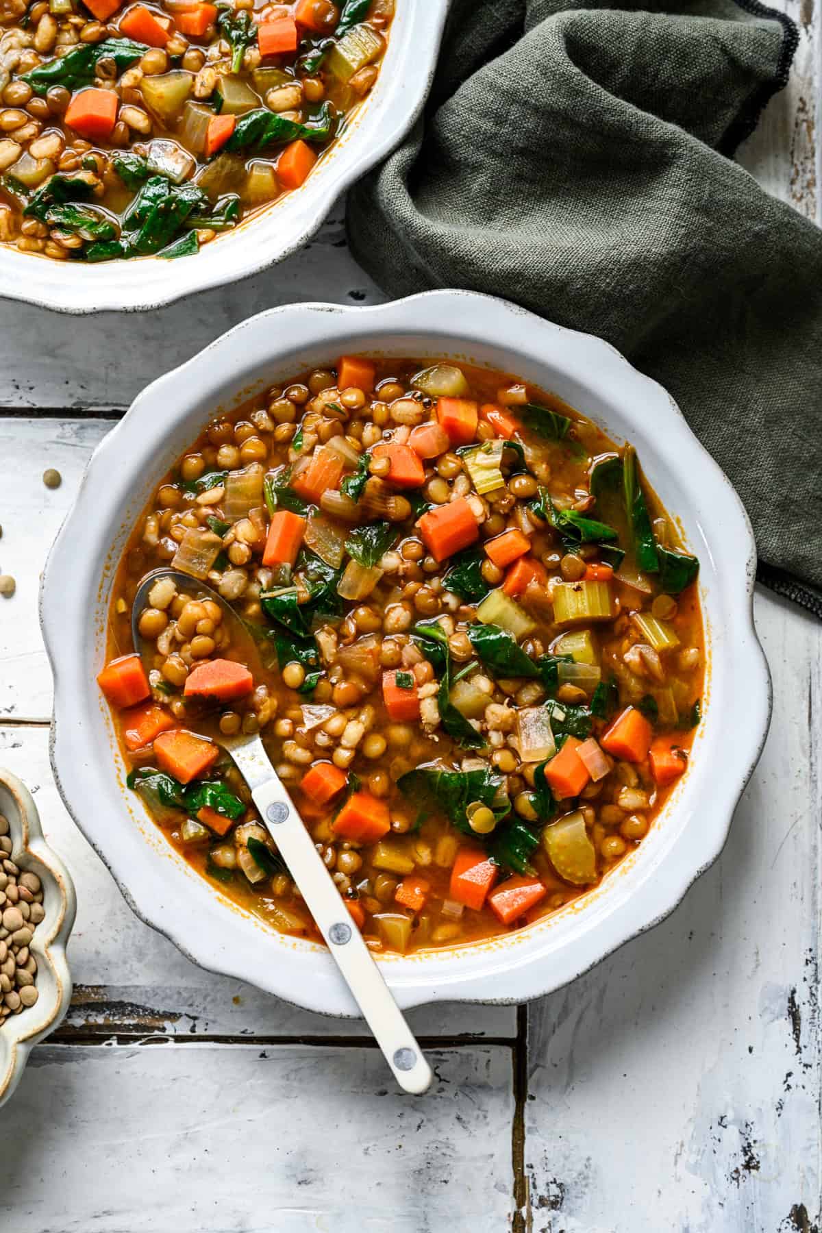 Lentil Barley Soup in a white bowl with a white spoon.