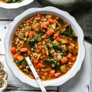 Lentil Barley Soup in a white bowl with a white spoon.