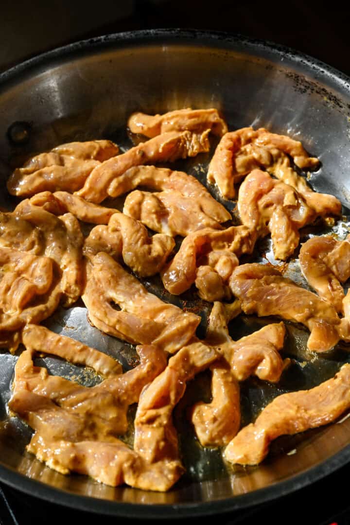 Overhead view of peanut-marinated chicken in a pan before cooking.