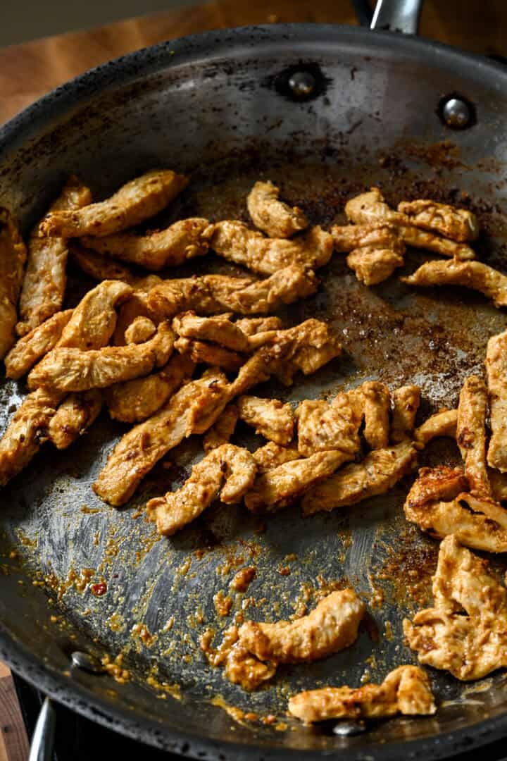 Overhead view of chicken cooking in a pan.