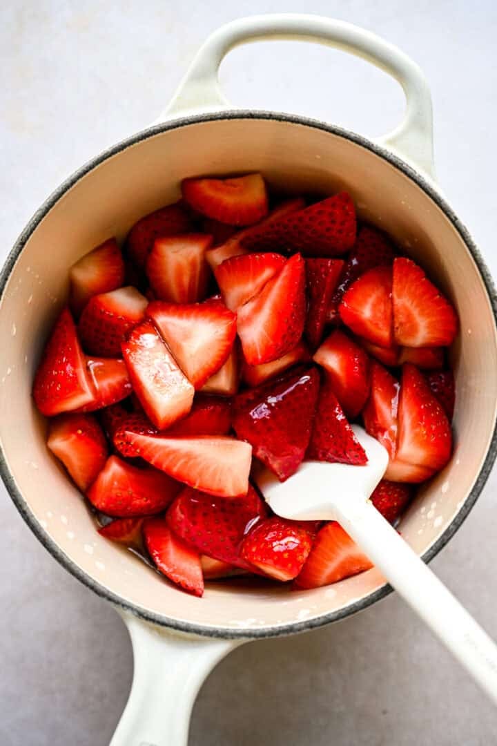 Strawberry syrup ingredients in a white pot before cooking.