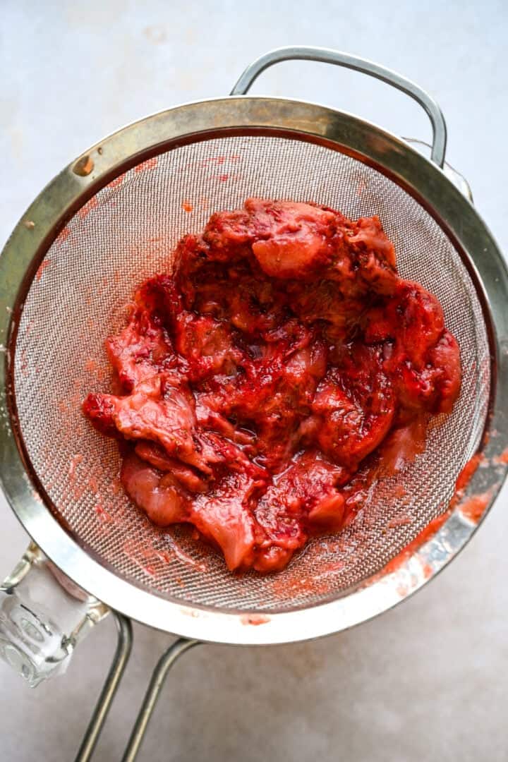 Strawberries in a strainer after straining the syrup.