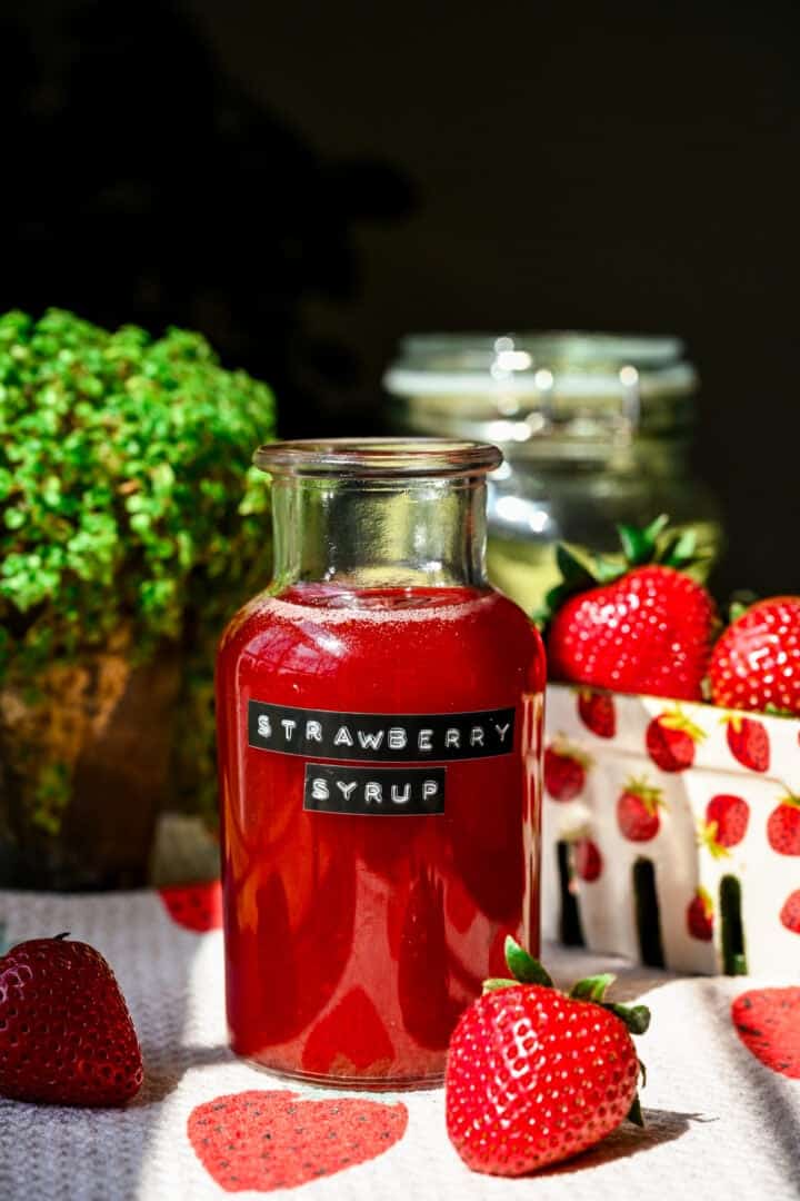 Homemade strawberry syrup in a jar with a label.