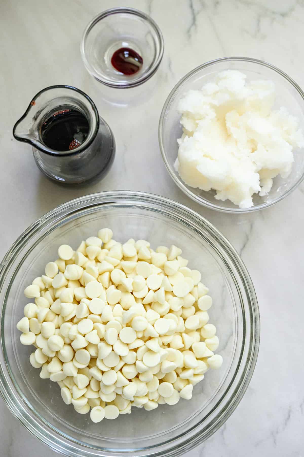 white chocolate chips, coconut oil, tart cherry concentrate and red food coloring all in separate bowls.