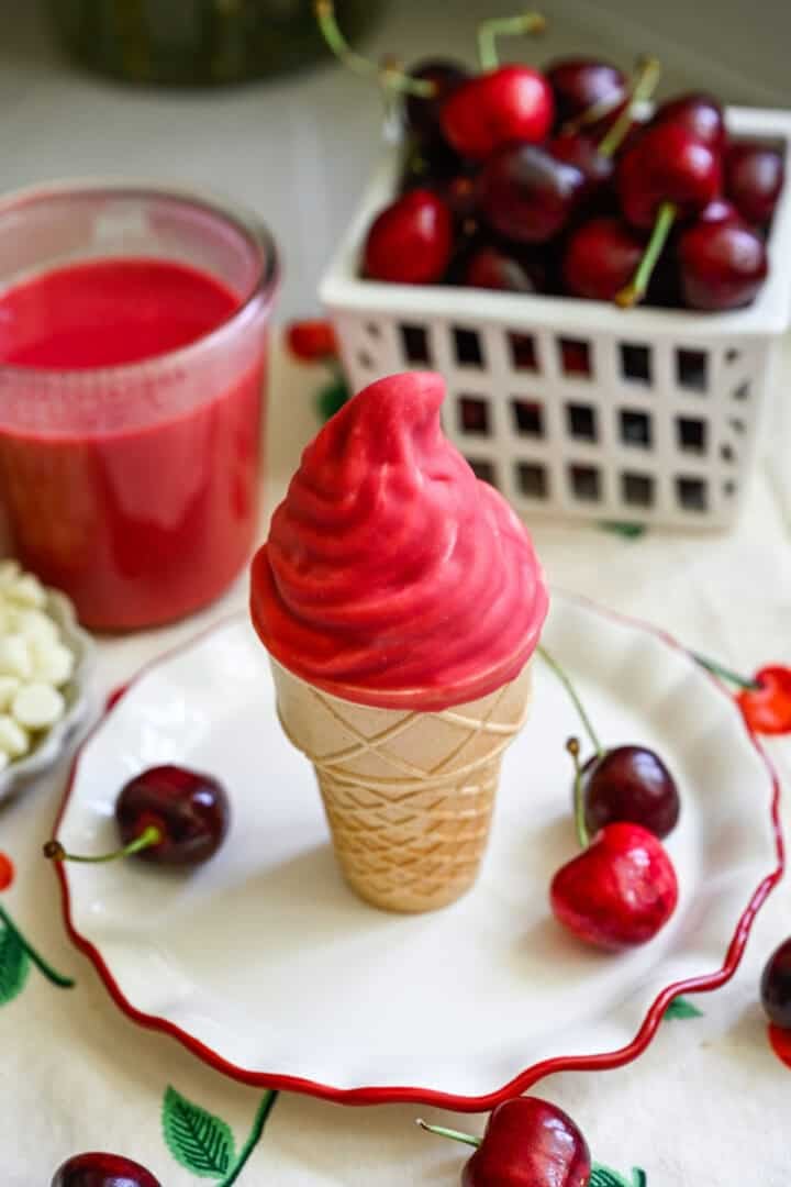 Ice cream cone with vanilla swirl dipped in homemade cherry magic shell.