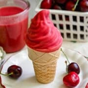 Ice cream cone with vanilla swirl dipped in homemade cherry magic shell.