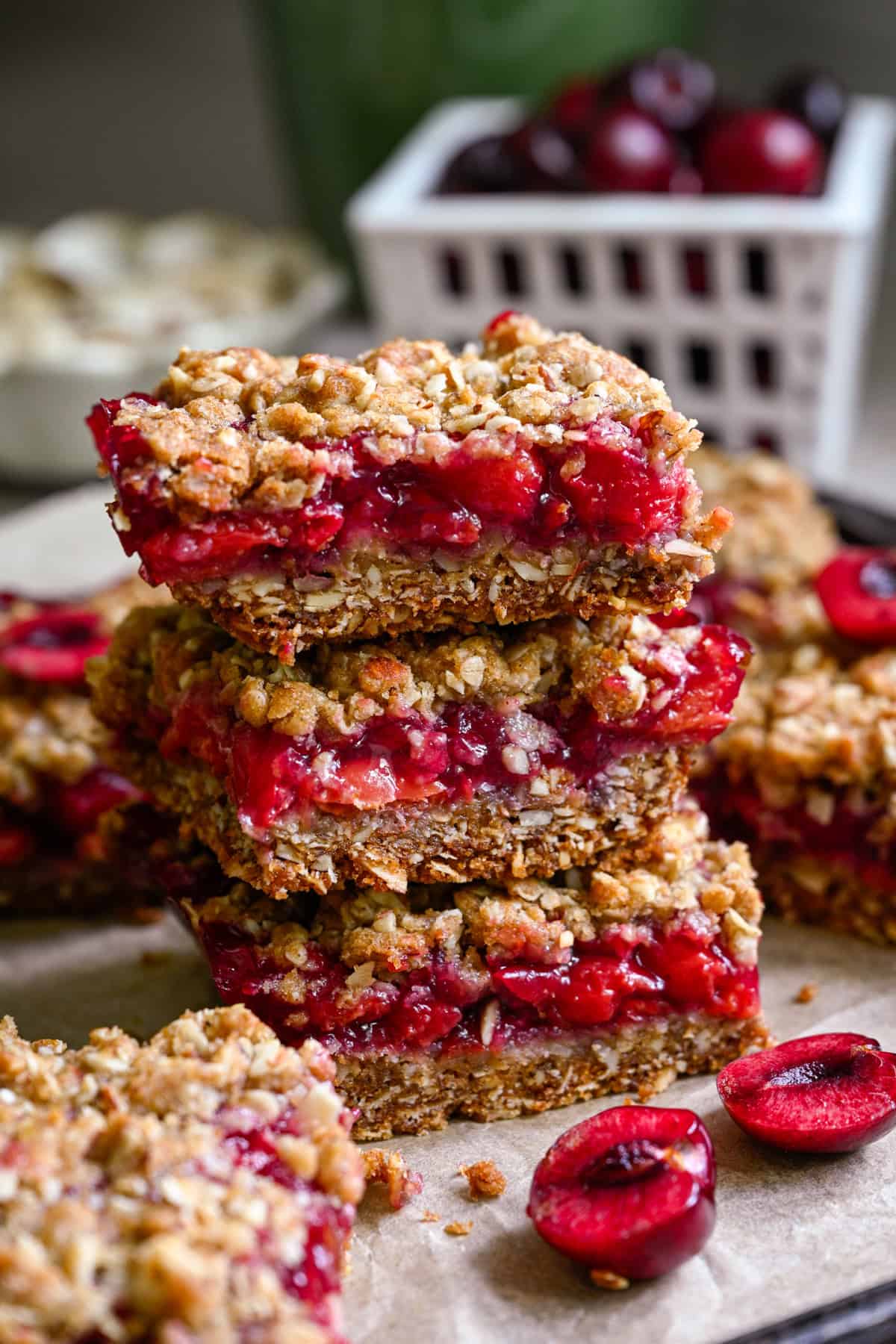 Close up of a stack of 3 cherry pie bars with fresh cherries in background.