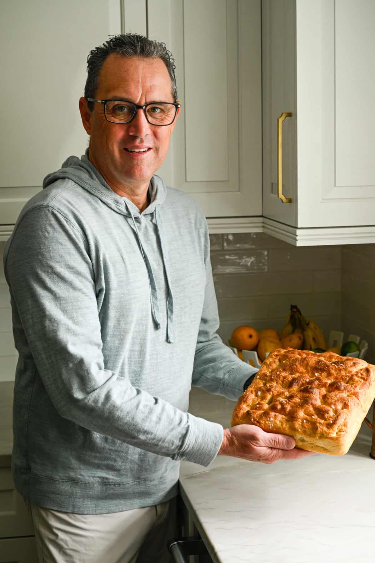 My dad in the kitchen holding a loaf of homemade focaccia.