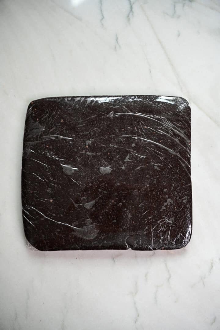 Oreo cookie dough wrapped in plastic wrap in a rectangle.
