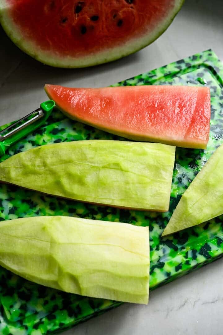 Overhead view of watermelon rinds on a cutting board.