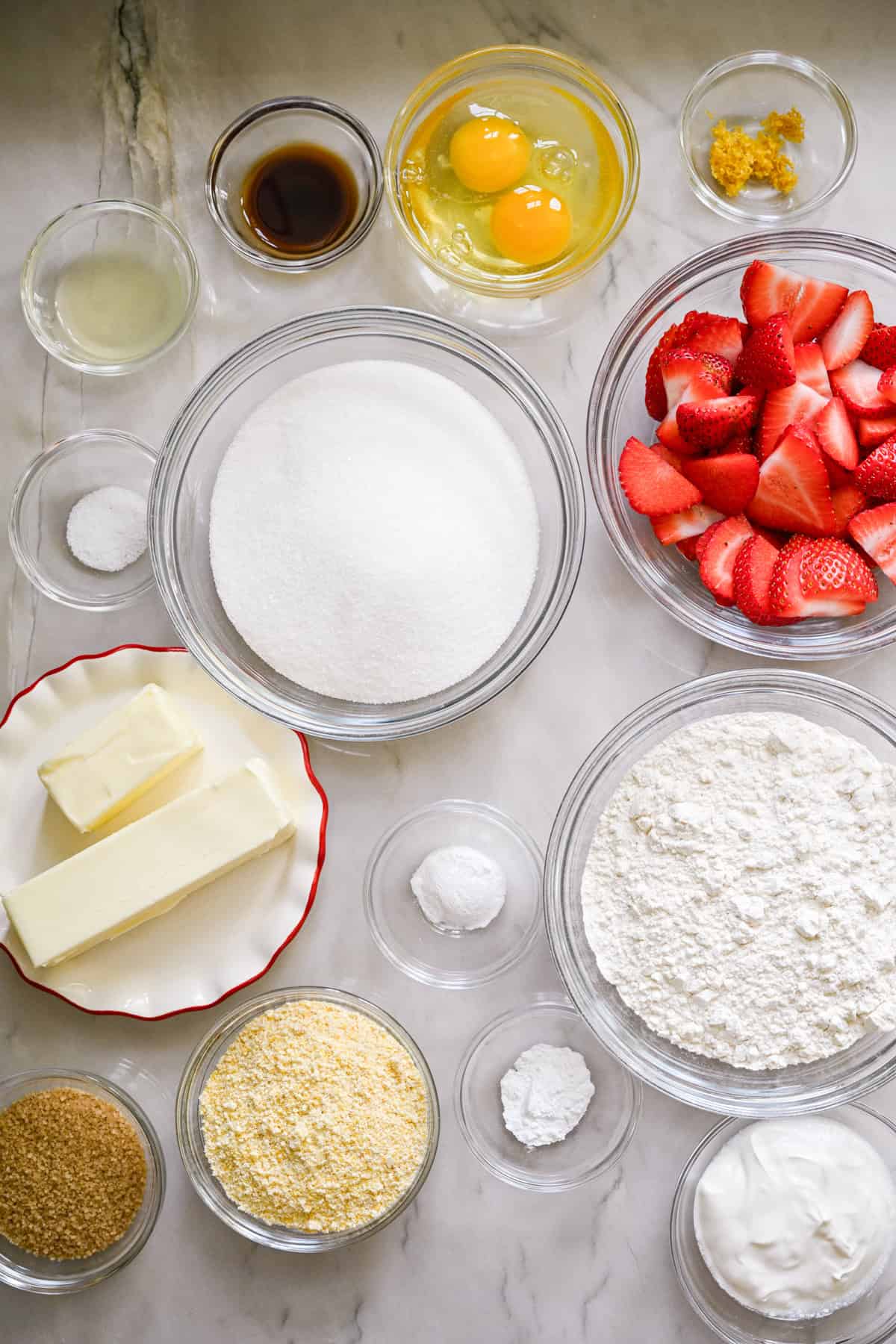 Overhead view of ingredients for strawberry cornmeal cake in small prep bowls.