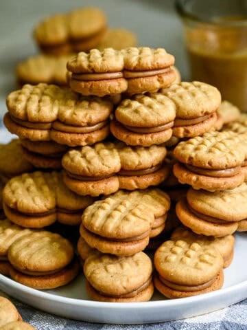 A big stack homemade nutter butters on a white plate.