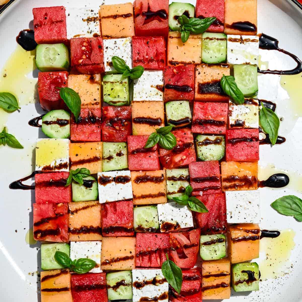 overhead view of watermelon checkerboard salad with squares of melon, cucumber, tomato and feta.