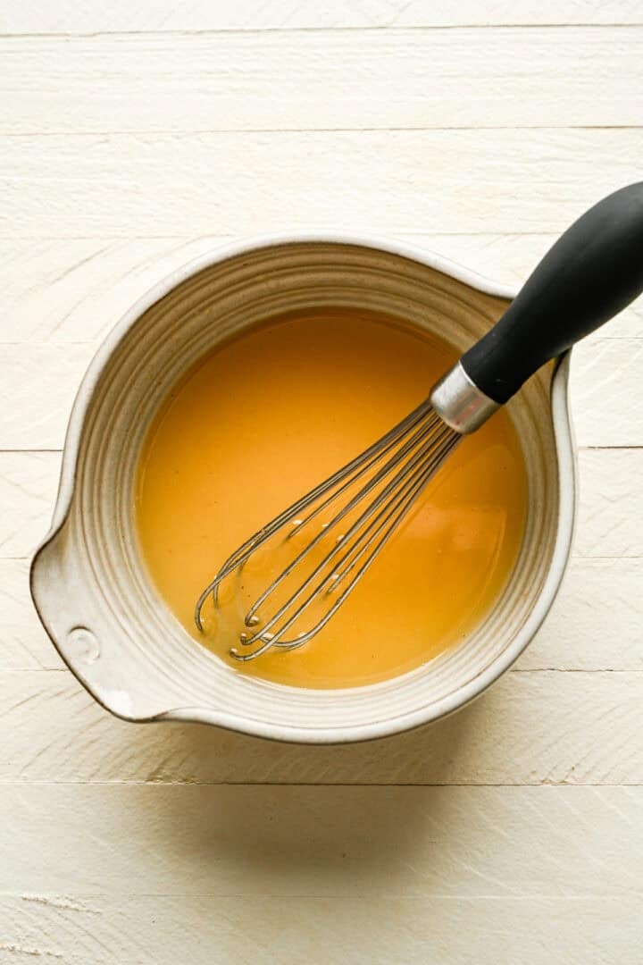 dressing whisked together in a bowl with whisk.