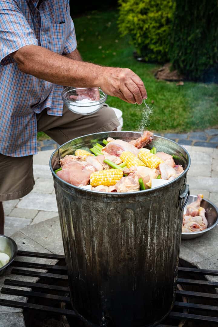 Sprinkling salt into a garbage can filled with corn, chicken and clams.