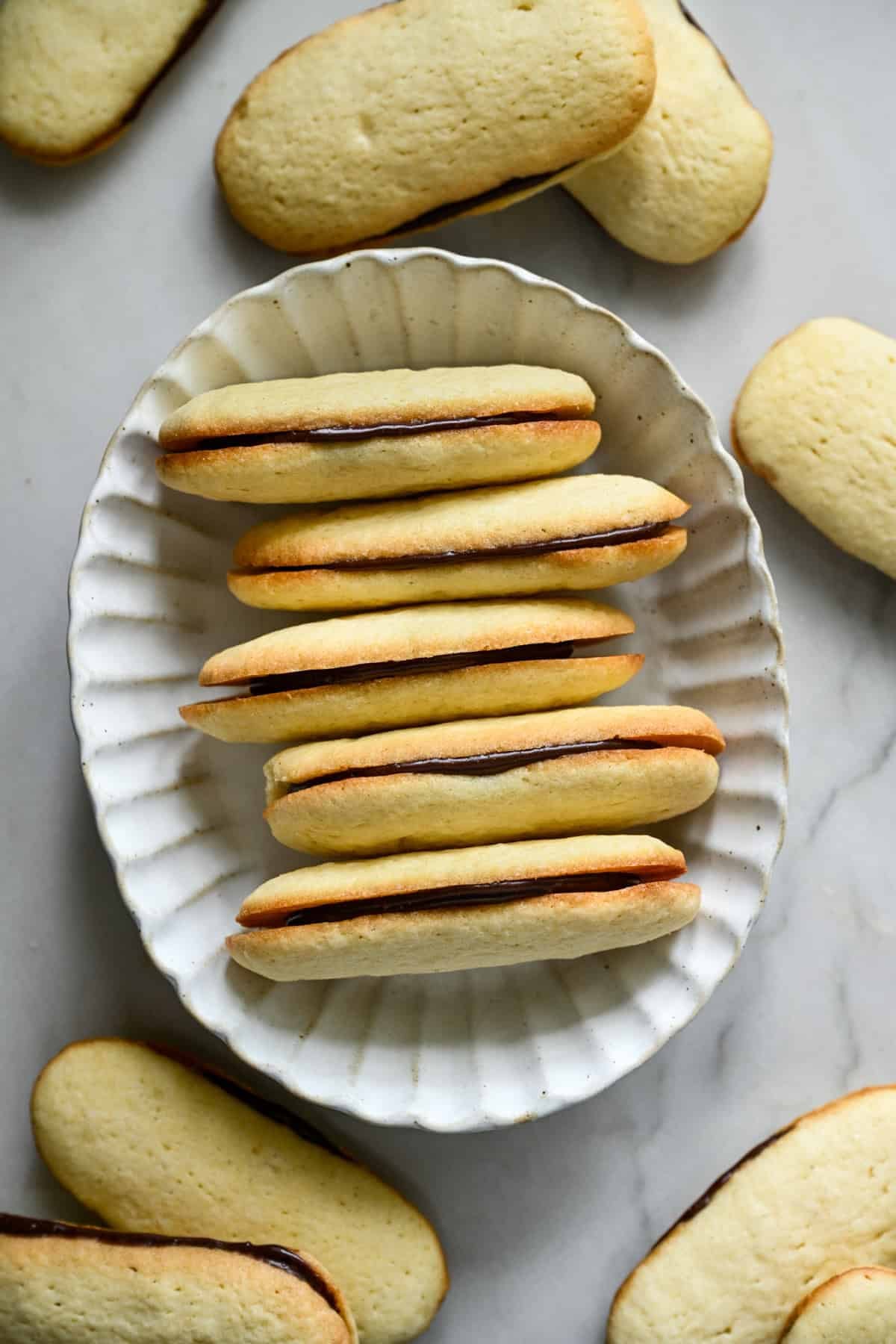 overhead view of a stack of homemade milano cookies in a white oval bowl. 