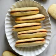 overhead view of a stack of homemade milano cookies in a white oval bowl.