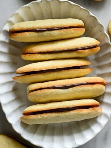 overhead view of a stack of homemade milano cookies in a white oval bowl.