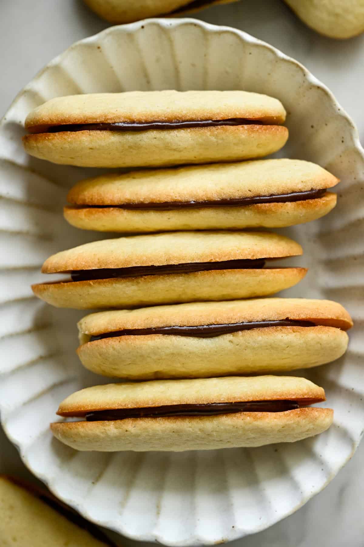 overhead view of a stack of homemade milano cookies in a white oval bowl.
