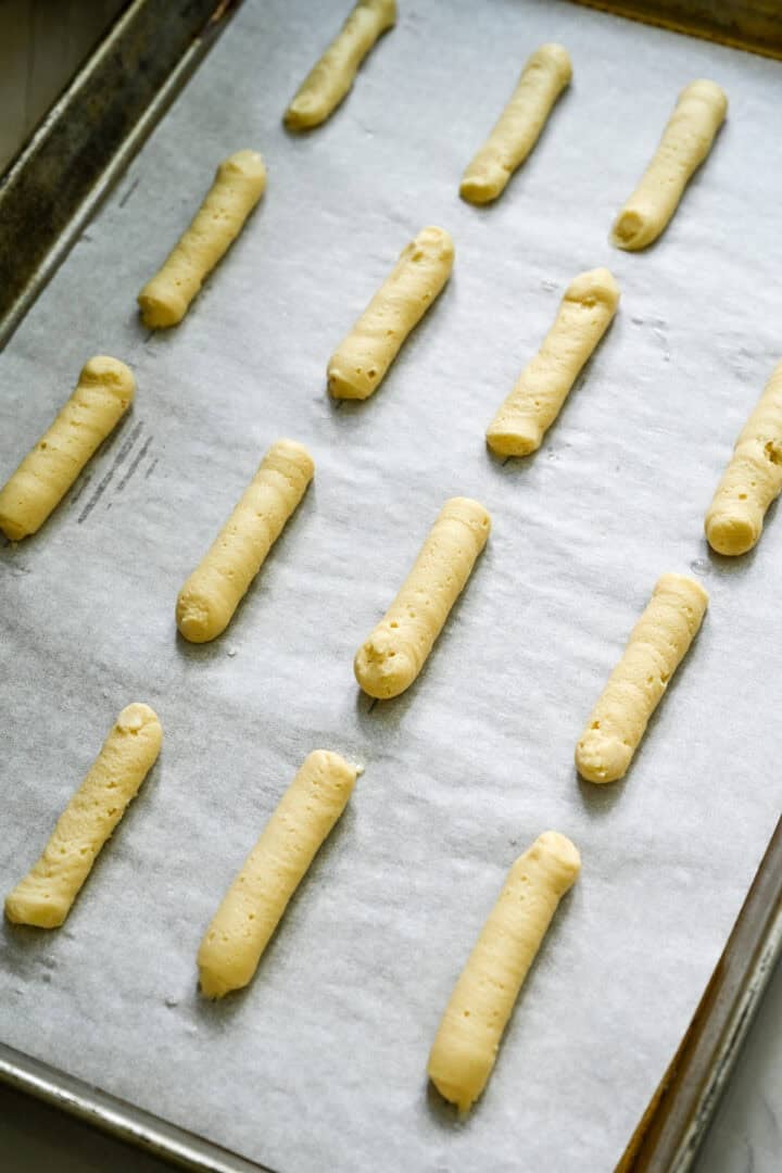 milano cookie dough piped into straight lines on a baking sheet.