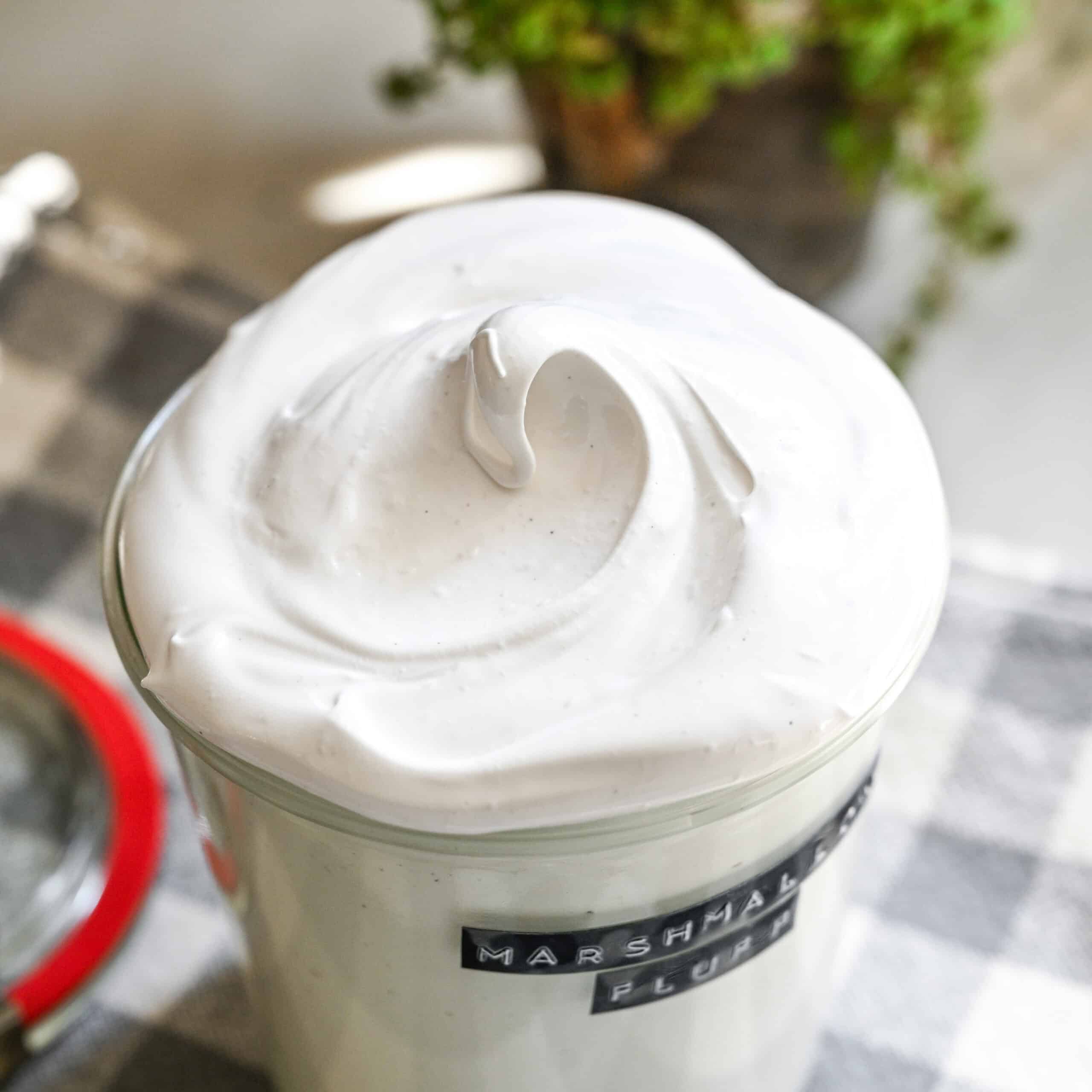 Close up view of homemade marshmallow fluff in a glass jar.