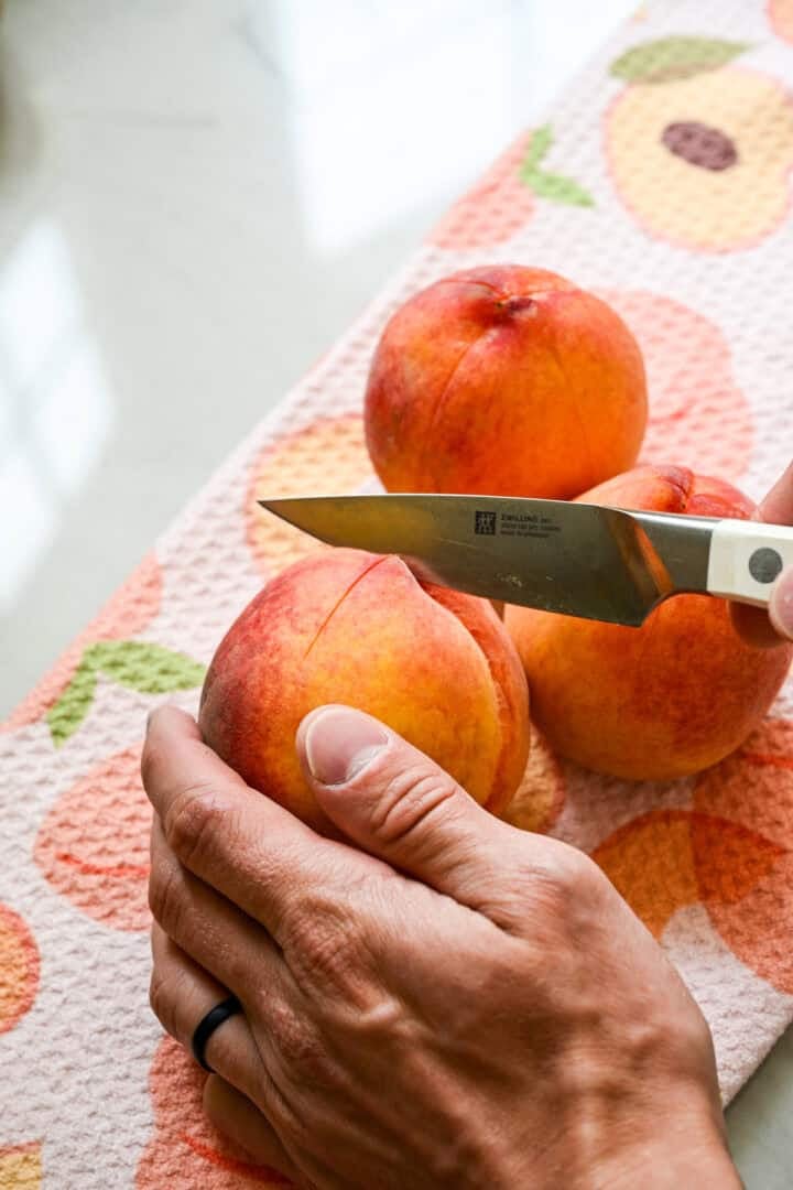 Cutting an x into the bottom of a peach.