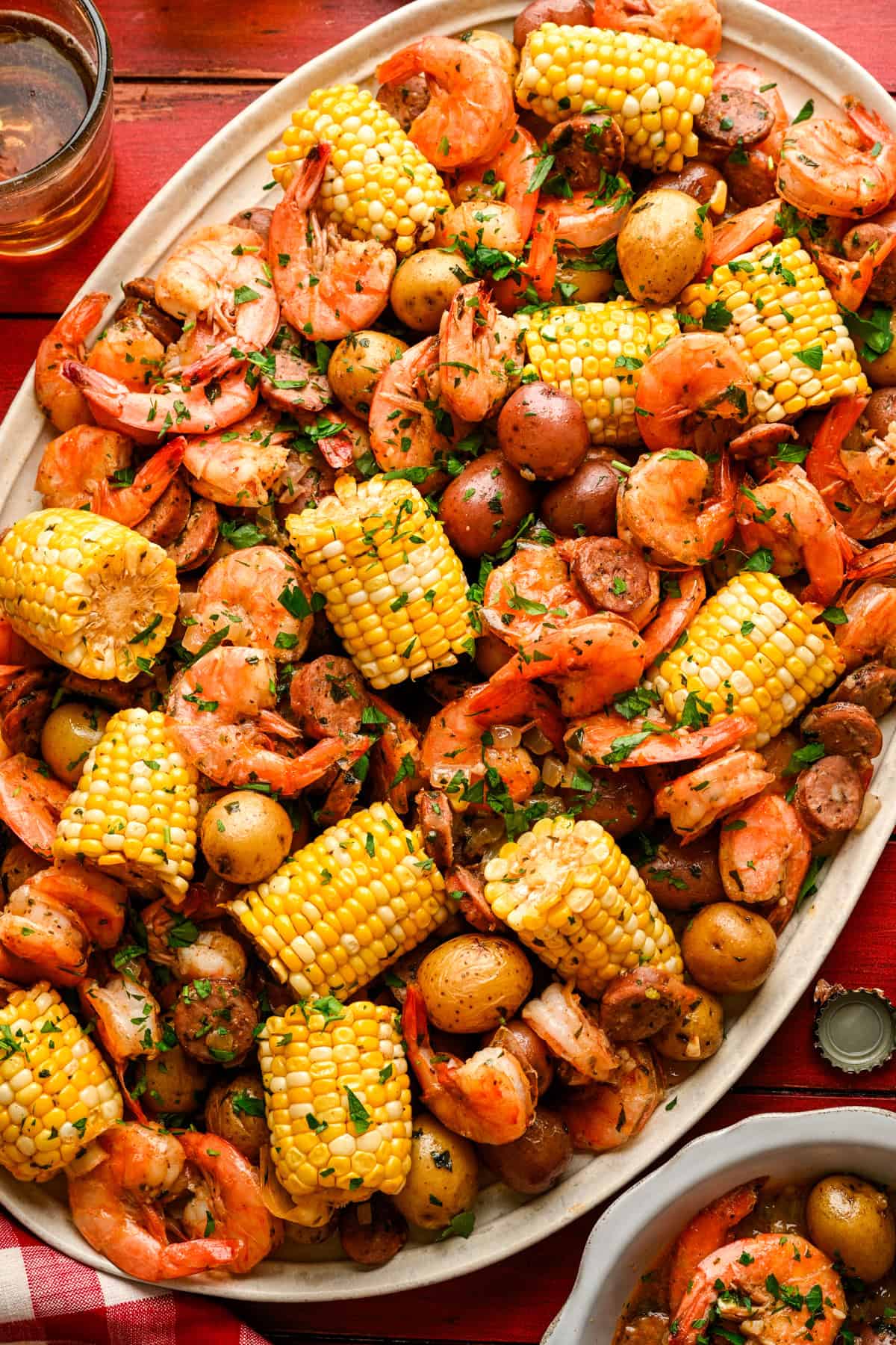 Overhead view of sheet pan shrimp boil on a platter with corn, shrimp, sausage and potatoes.