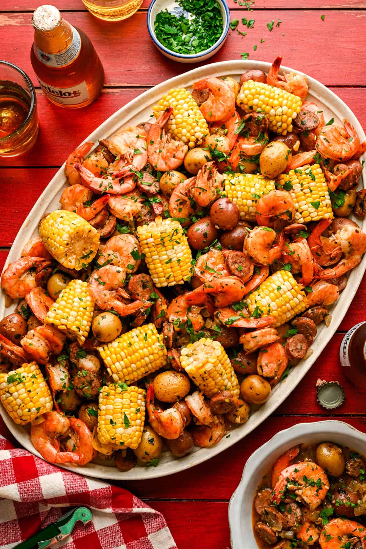 Overhead view of sheet pan shrimp boil on a platter with corn, shrimp, sausage and potatoes.