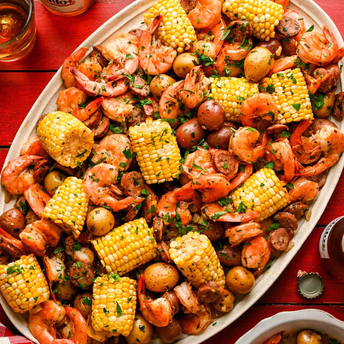 Overhead view of sheet pan shrimp boil on a platter with corn, shrimp, sausage and potatoes.