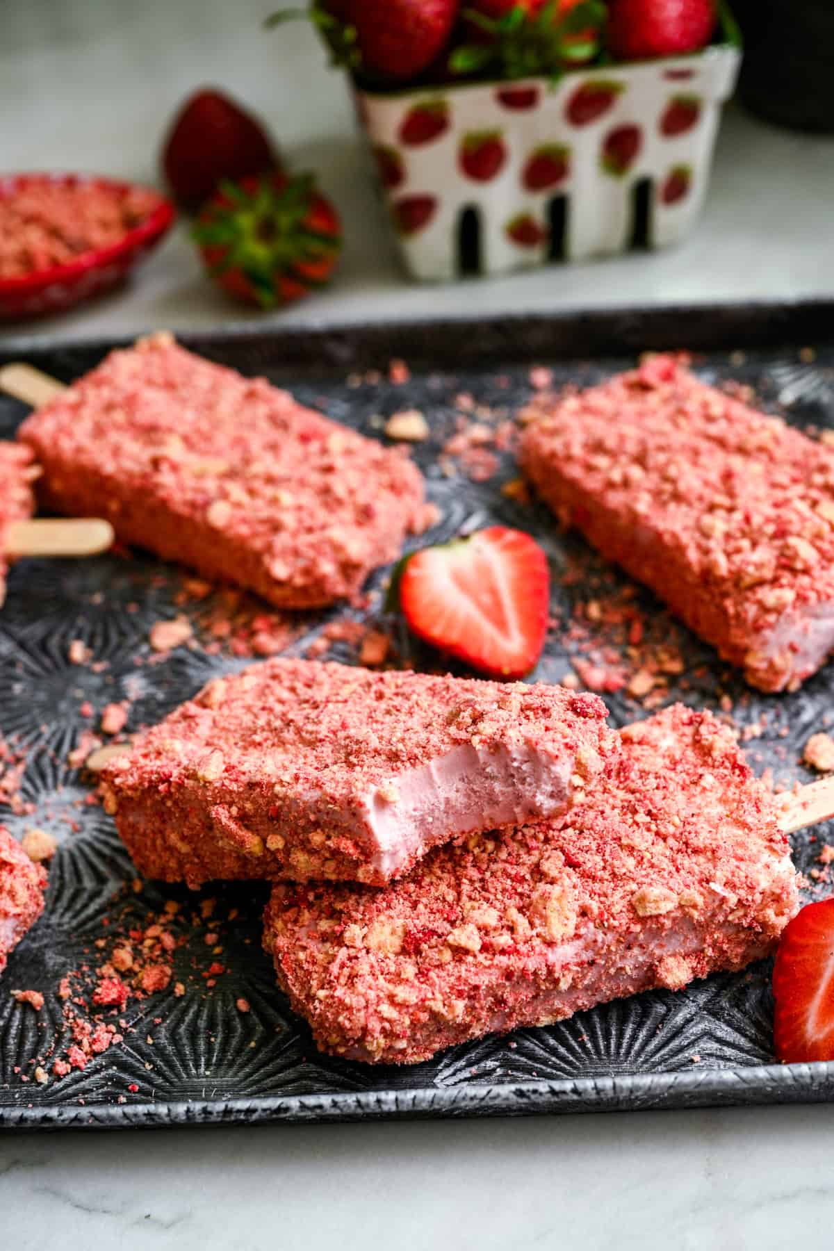 2 strawberry shortcake ice cream pops stacked on top of each other with a bite taken out of the top one.