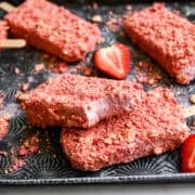 2 strawberry shortcake ice cream pops stacked on top of each other with a bite taken out of the top one.