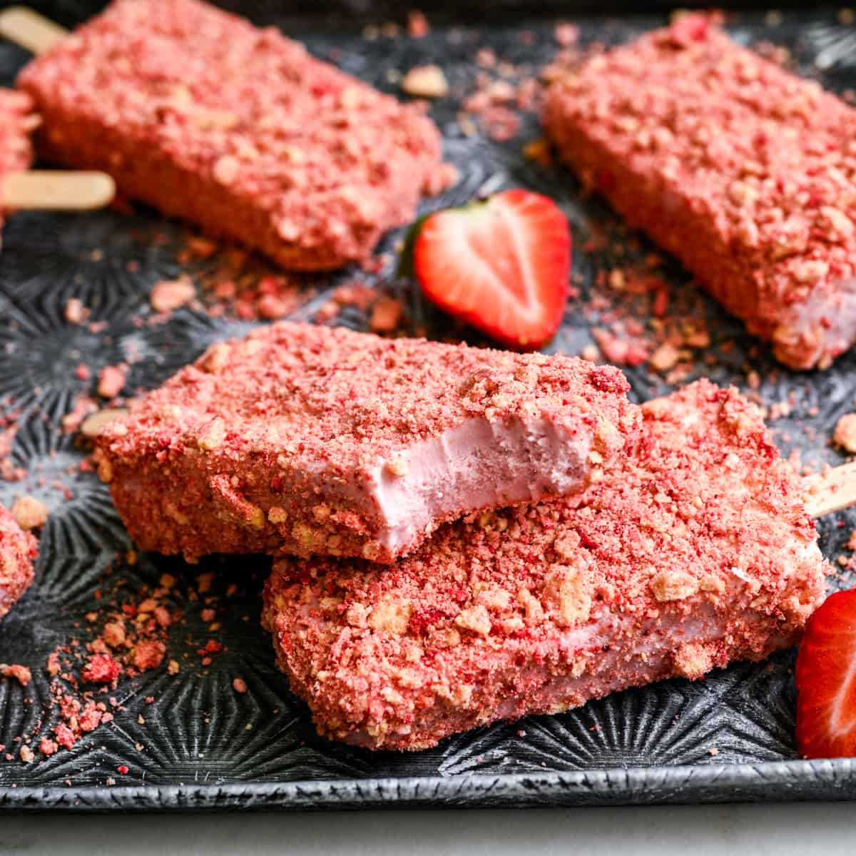 2 strawberry shortcake ice cream pops stacked on top of each other with a bite taken out of the top one.