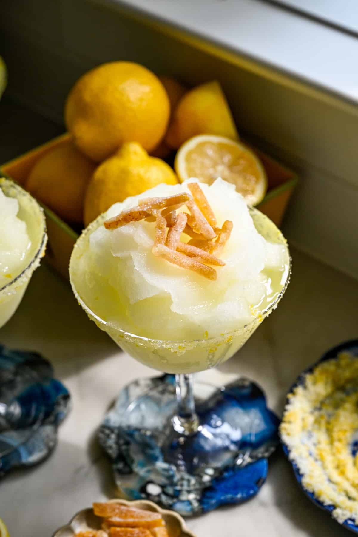 close up view of frozen limoncello cocktail in a coupe glass with candied yuzu peel garnish.
