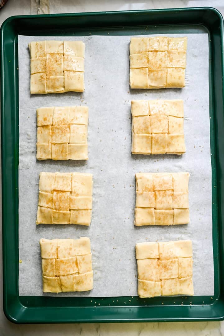 Overhead view of 8 unbaked apple hand pies on a parchment-lined sheet pan.
