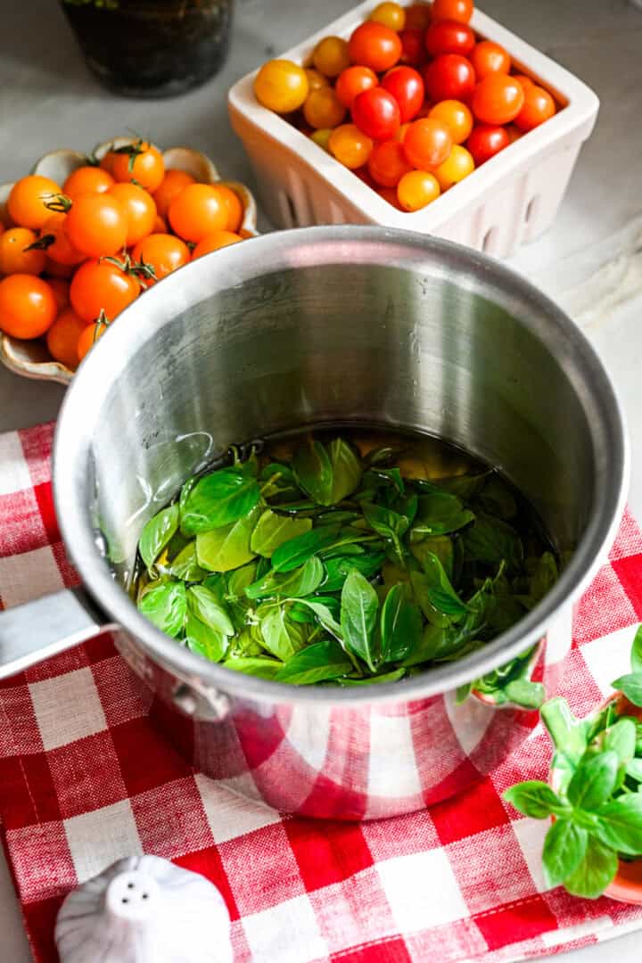 Fresh basil infusing in olive oil in a pot.