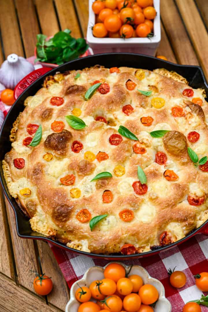 Overhead view of tomato basil focaccia in a red cast iron skillet.