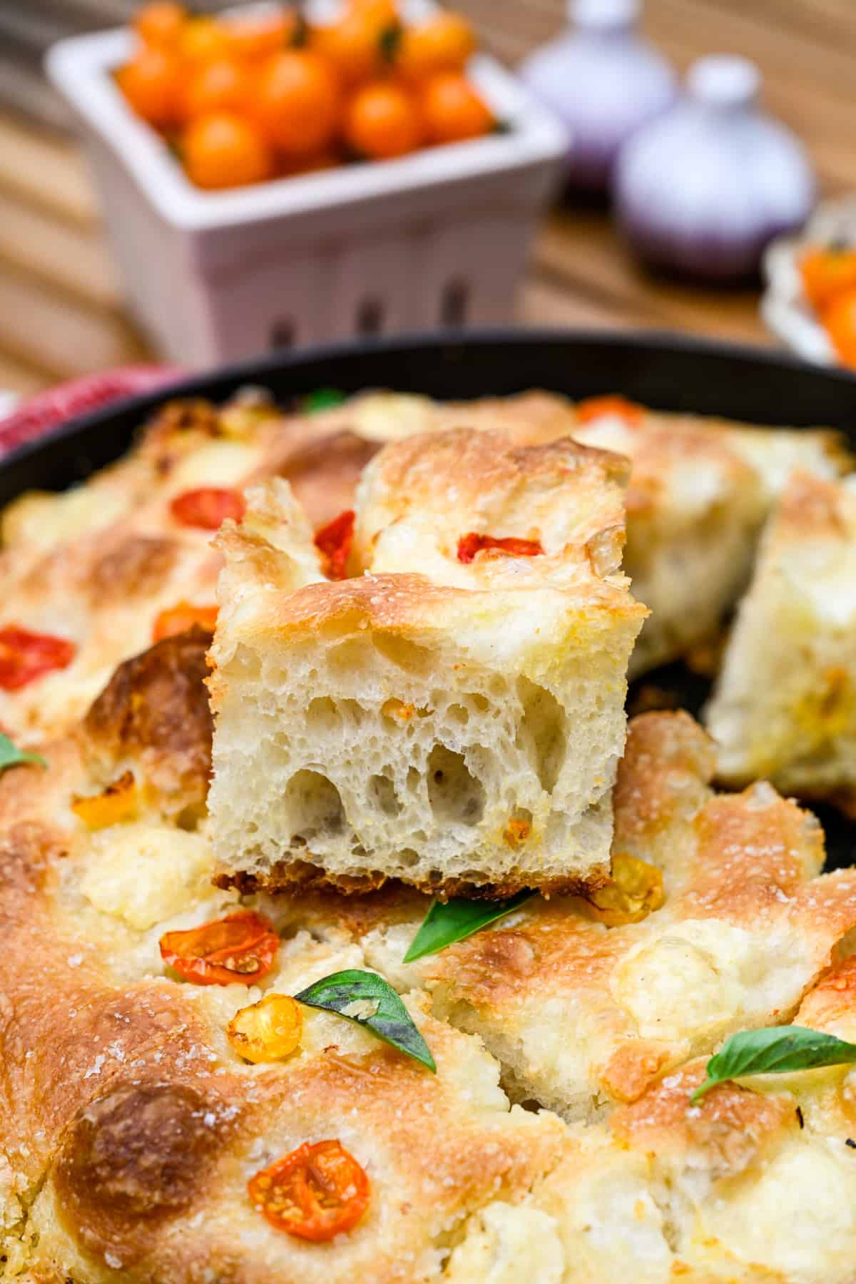 A slice of tomato basil focaccia on top of the rest of the bread.