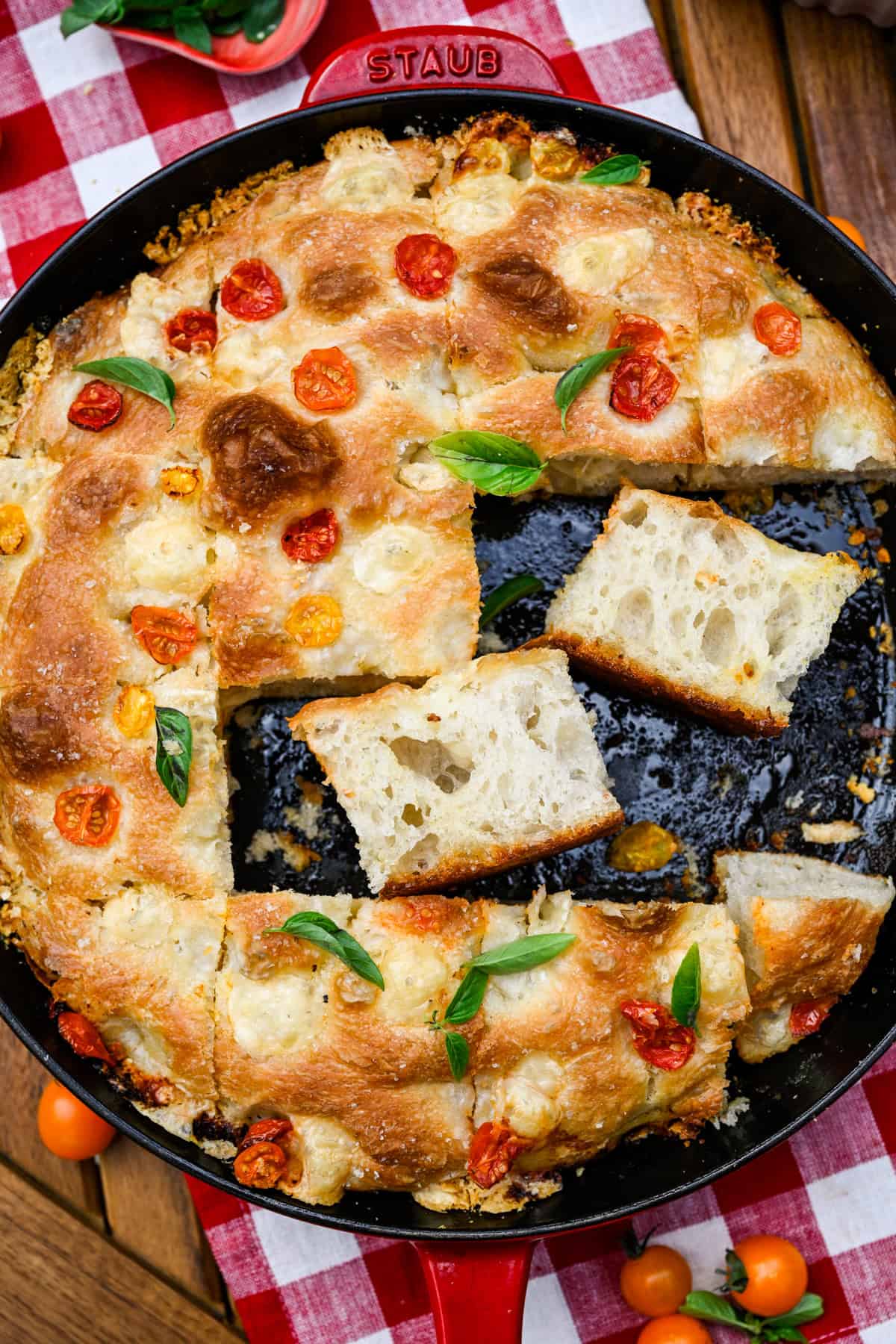 Tomato basil focaccia in a skillet with two slices laying on their sides.