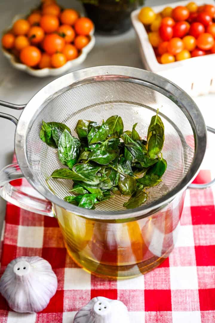 straining the basil out of the oil.