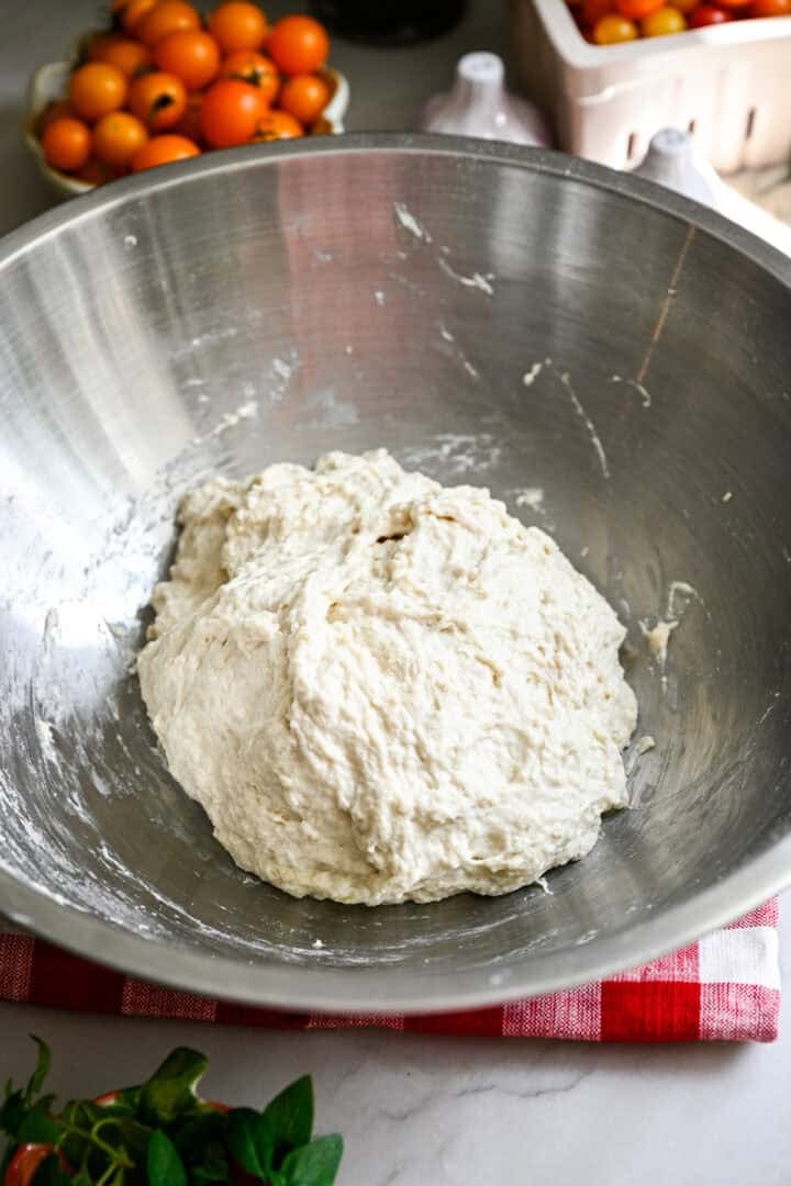 focaccia dough in a stainless steel bowl.