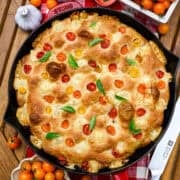 Overhead view of tomato basil focaccia in a red cast iron skillet.
