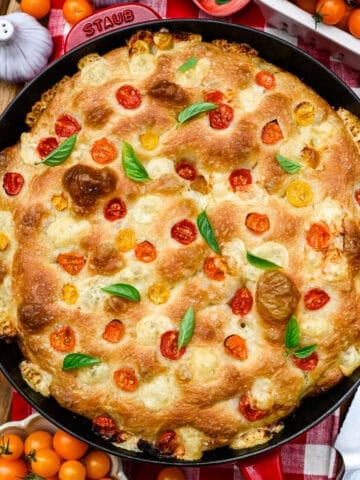Overhead view of tomato basil focaccia in a red cast iron skillet.