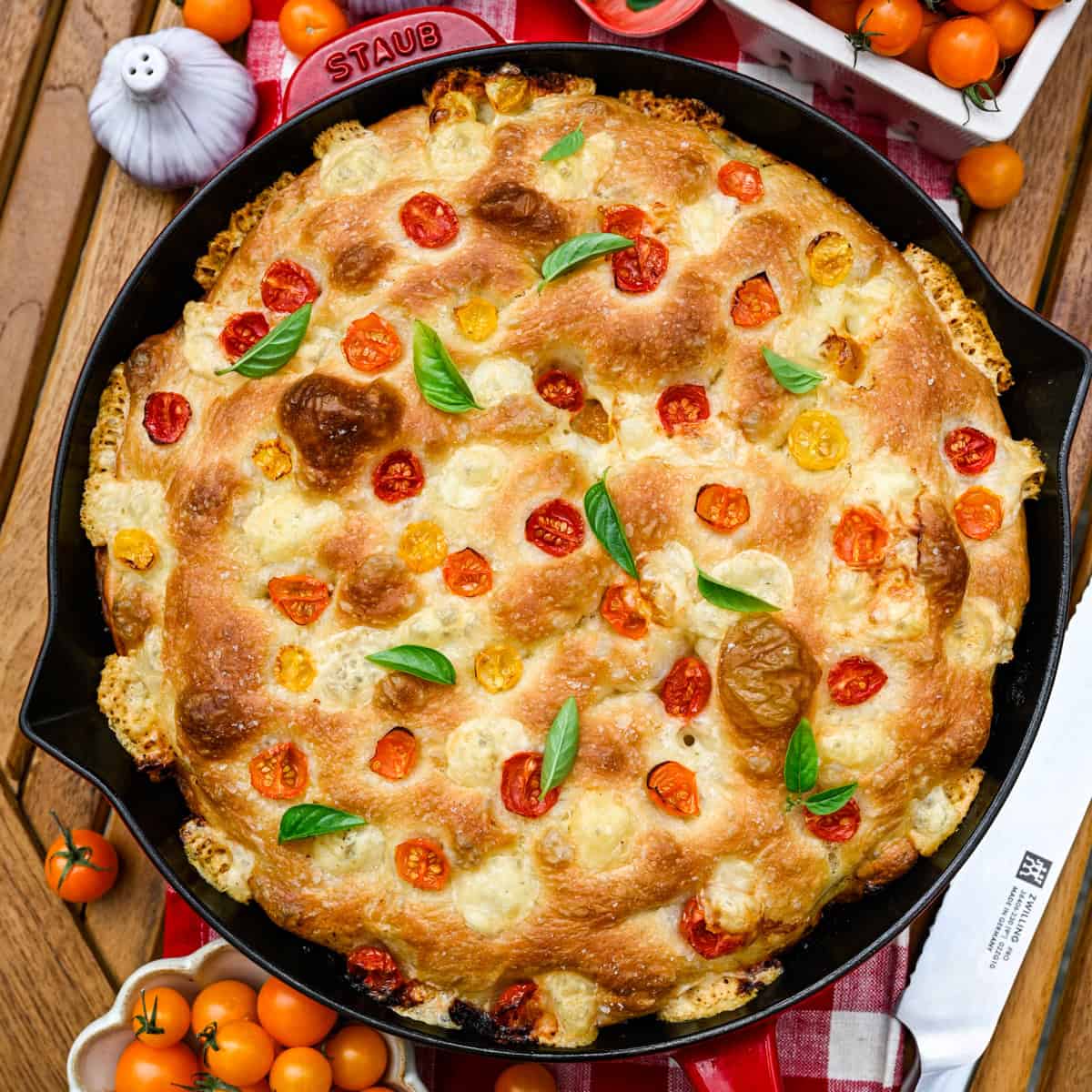 Overhead view of tomato basil focaccia in a red cast iron skillet.