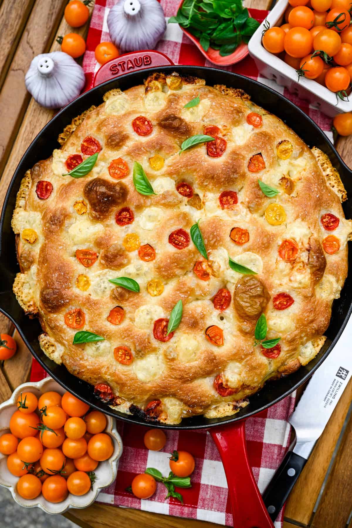 Overhead view of tomato basil focaccia in a red cast iron skillet.