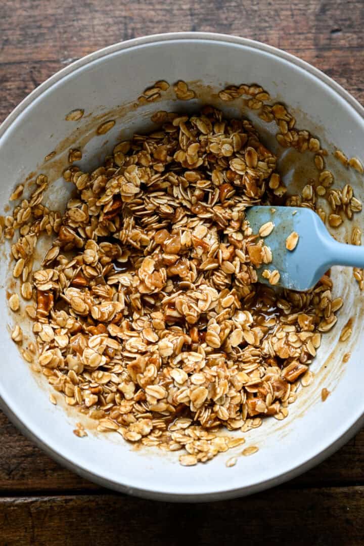 Oat mixture stirred with the butter and syrup until sticky and clumped together.