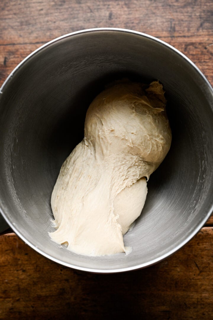 Soft, stretchy pretzel dough starting to come together in a stainless steel mixer bowl.